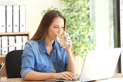 Woman at Laptop drinking ice water.