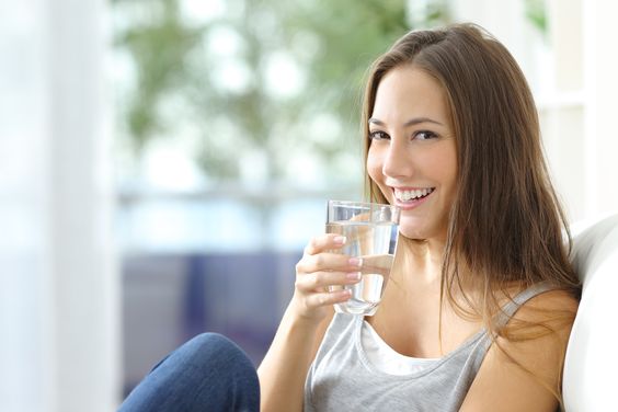 Girl drinking purified water at home.